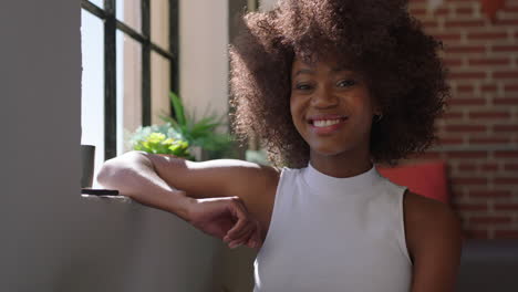 retrato de una mujer afroamericana feliz mirando a la cámara sonriendo disfrutando de un estilo de vida exitoso relajándose en casa mujer negra con un peinado afro de moda