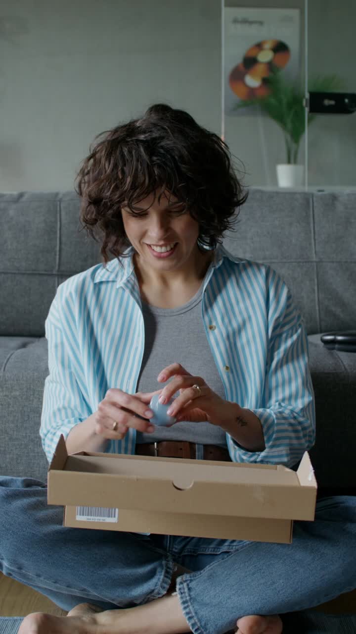 una mujer desempaquetando un regalo en casa.