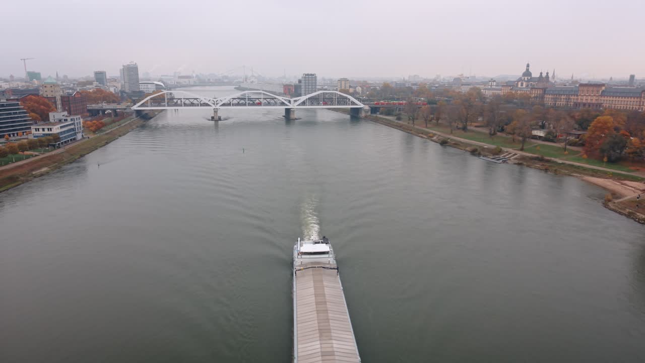 Aerial Tracking Shot of Large Cargo Barge Sailing Down Rhine River Towards Mannheim Palace