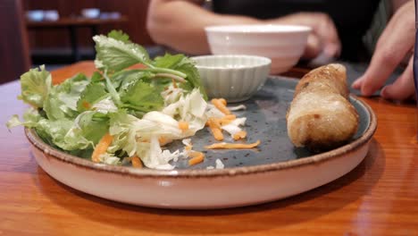 fresh vegetables on a blue plate, with cilantro, cabbage, and shredded carrots