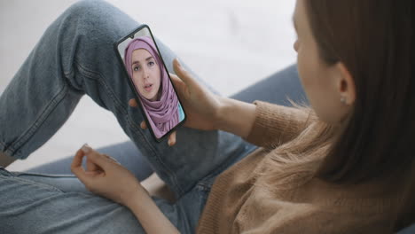 Frau-Nutzt-Medizinische-App-Auf-Dem-Smartphone-Und-Berät-Sich-Per-Videokonferenz-Mit-Einer-Arabischen-Muslimischen-Frau-Im-Hijab-Arzt.-Frau-Nutzt-Online-Chat,-Um-Mit-Familientherapeuten-Und-Einer-Coronavirus-Pandemie-Zu-Sprechen.