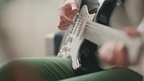 the hands of an unrecognizable woman learning to play the electric guitar