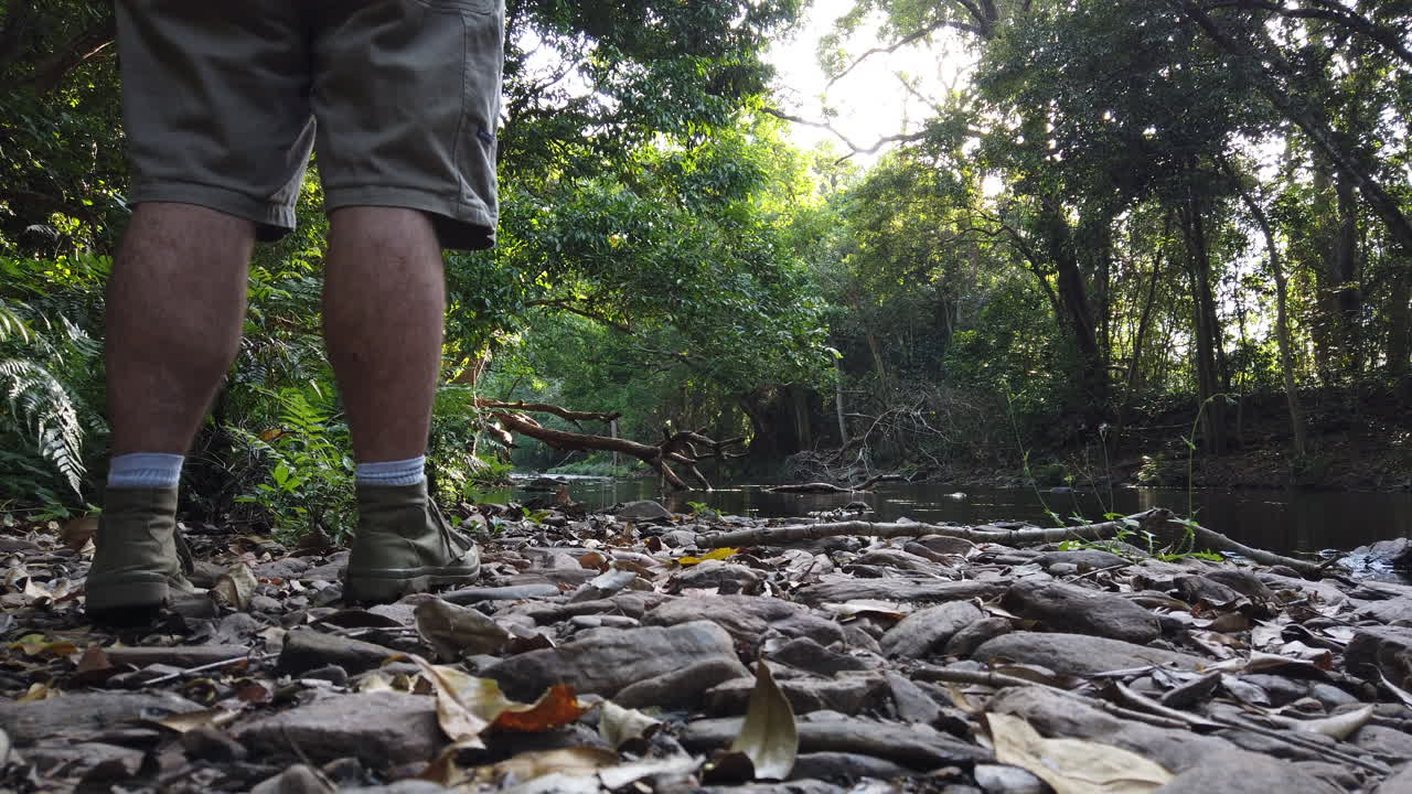 man walking to waters edge and looking upstream