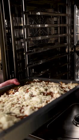 chef placing lasagna tray in oven