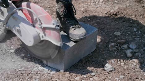 electric disc cutter being used to trim stone block outside on the ground