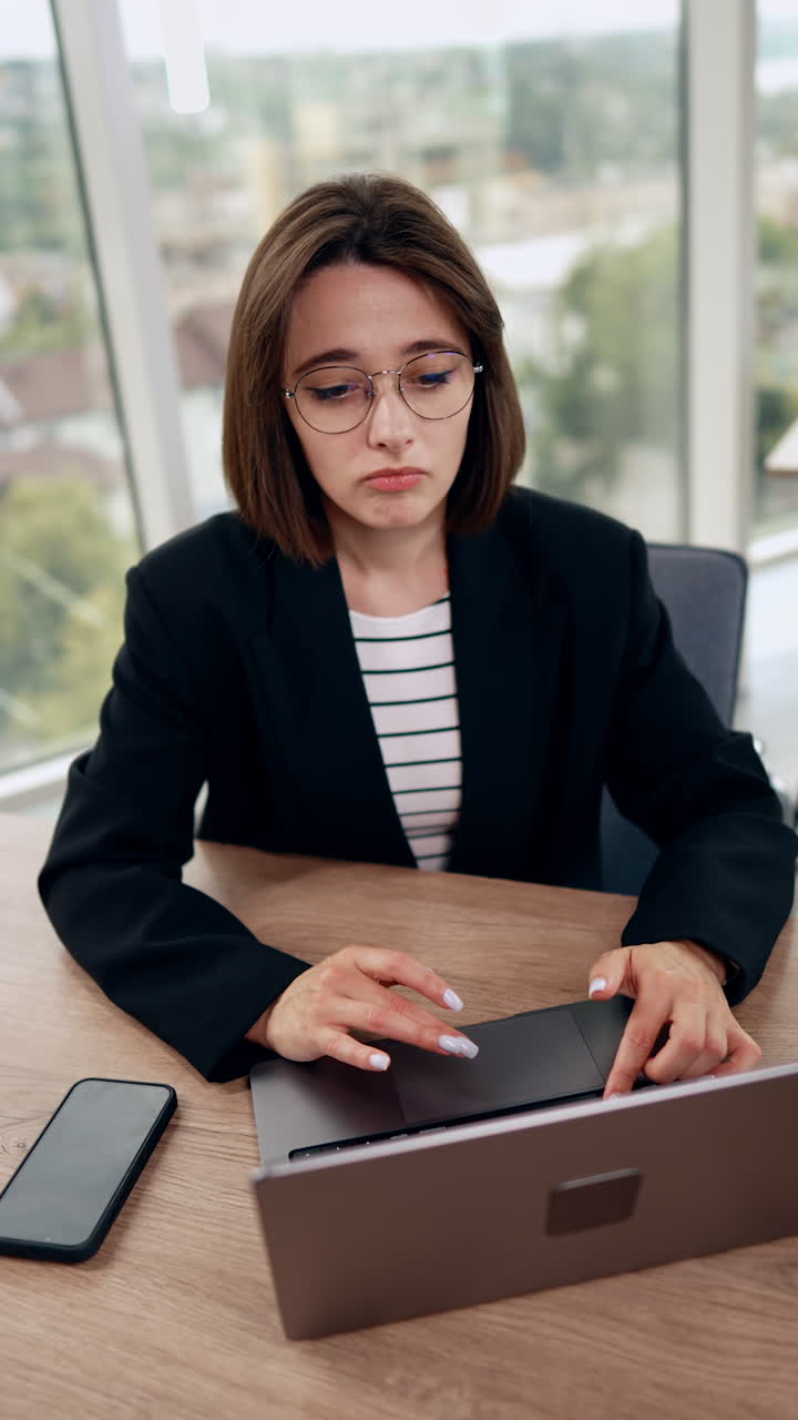 Busy working lady using her laptop. Portrait of a modern businesswoman in the office. Vertical video.