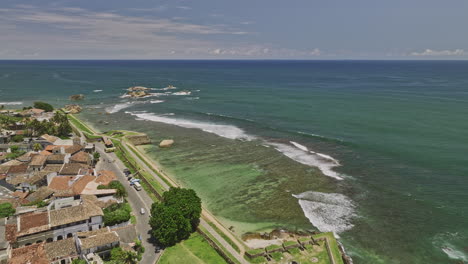 Galle-Sri-Lanka-Aerial-v1-fly-along-rampart-street-towards-coastal-lighthouse-capturing-historic-colonial-fort-on-the-peninsula,-beach,-cityscape-and-harbor-views---Shot-with-Mavic-3-Cine---April-2023