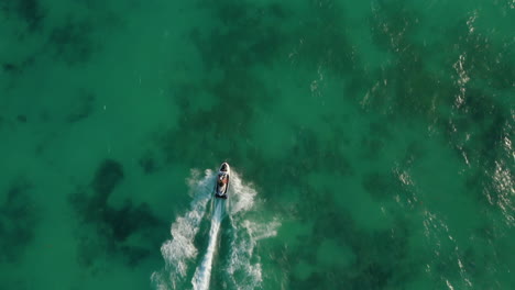 Couple-riding-jet-ski-on-the-calm-sea.-They-are-cruising-on-the-sea-with-waverunner.-Aerial-Birds-Eye-Overhead-Top-Down-View