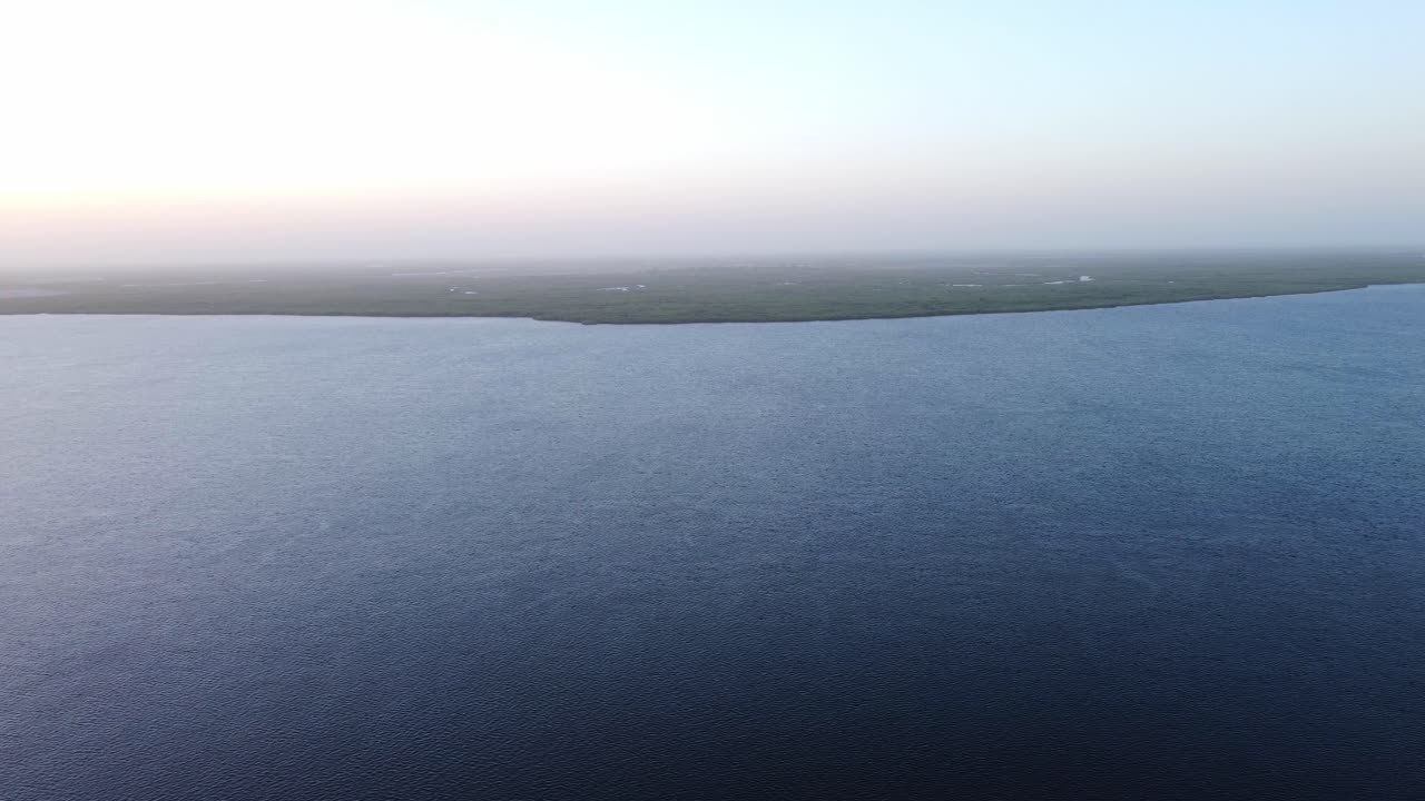 Aerial view of a calm river or lake with a misty horizon