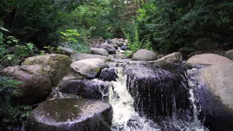 Reveal-shot-of-a-small-waterfall-in-the-middle-of-a-forest,-rack-focus