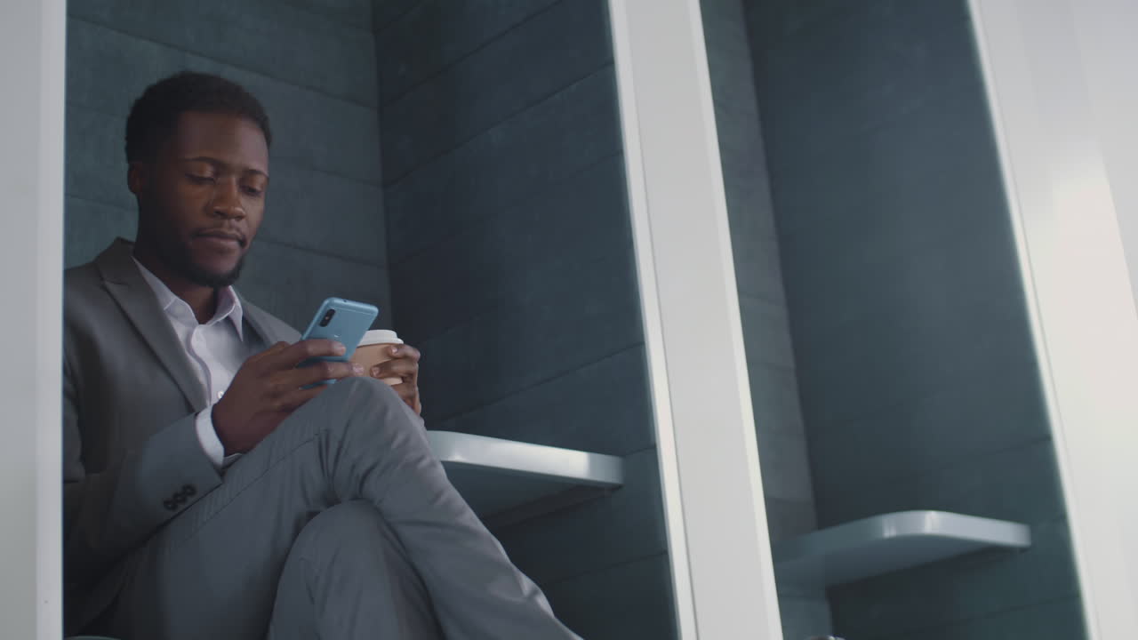 African-American Businessman Drinking Coffee and Using Smartphone