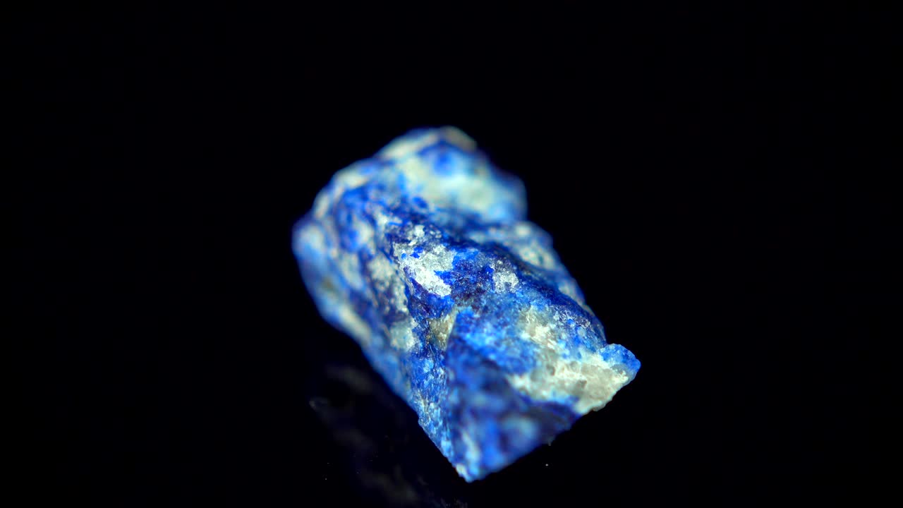 Girando continuamente um mineral azul (Lápis-Lazúli) sobre fundo preto