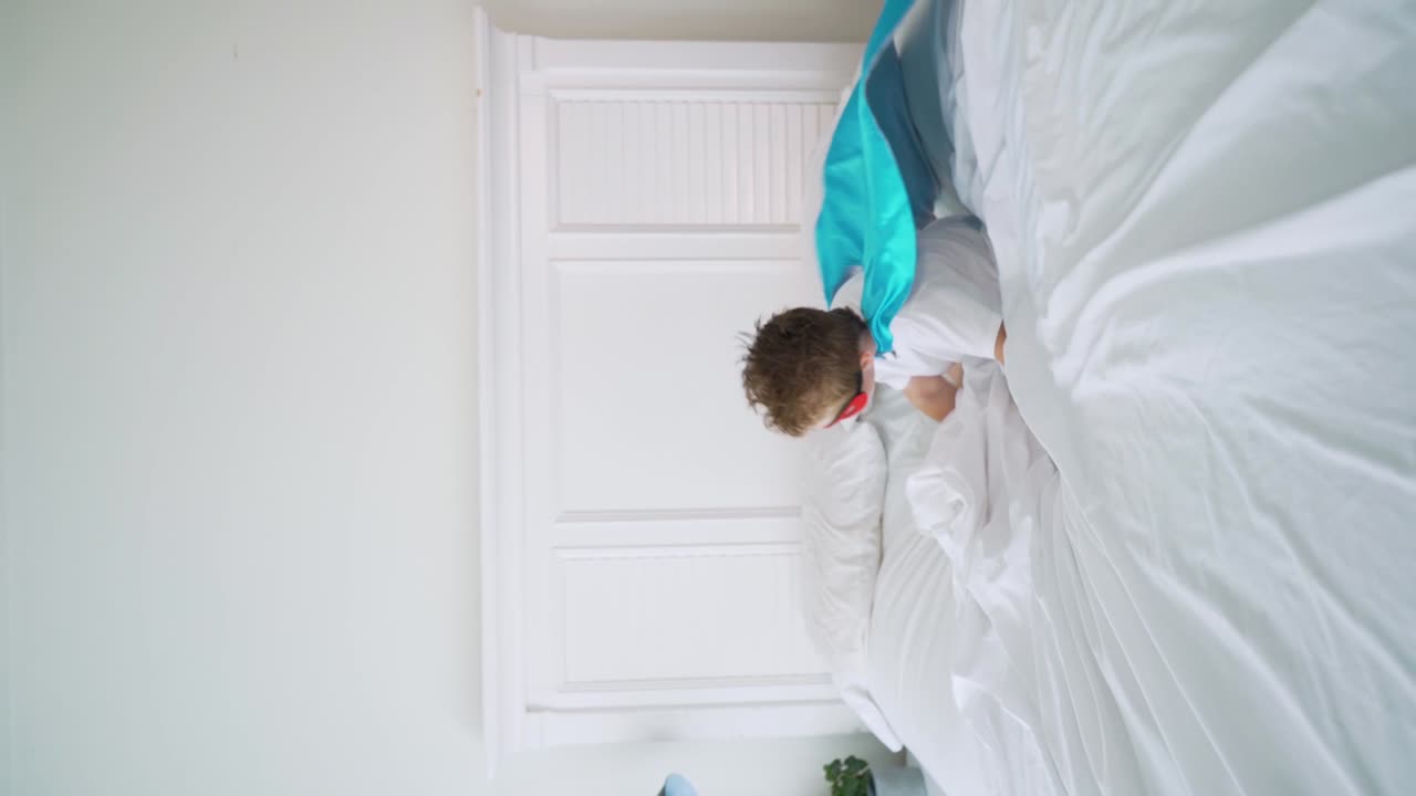 мальчик-супергерой прыгает на кровати