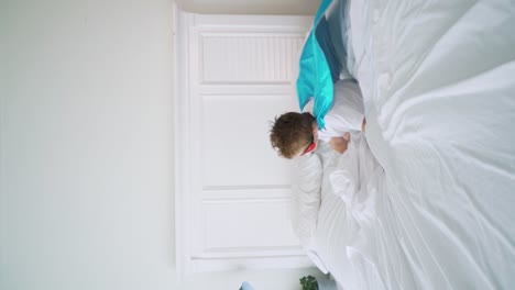 niño superhéroe saltando en la cama