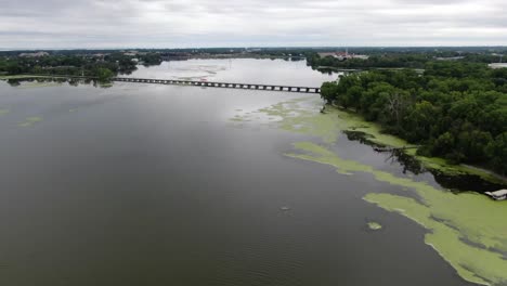 Vista-Aérea-Del-Lago-Cerca-De-Neenah,-Wisconsin,-Volando-Hacia-El-Sendero-De-Caballetes-Puente-Que-Cruza-El-Pequeño-Lago-Butte-Des-Morts