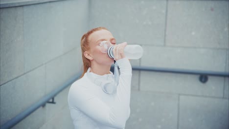 woman drinking water after exercise