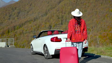 woman with a suitcase on a mountain road trip