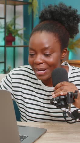 african american young woman blogger recording podcast smiling sitting on sofa using laptop at home