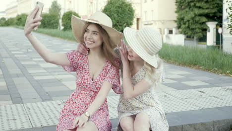 two young women taking selfies in a city park