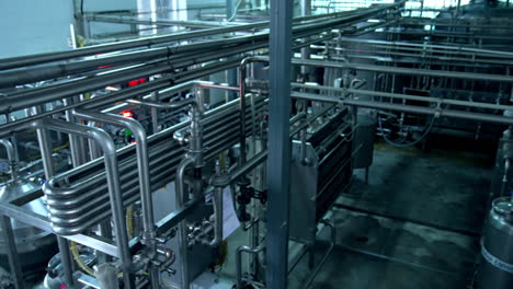 milk and water pipelines at a modern dairy factory. tanks, pipes and faucets close up. gradual lifting above the factory equipment.