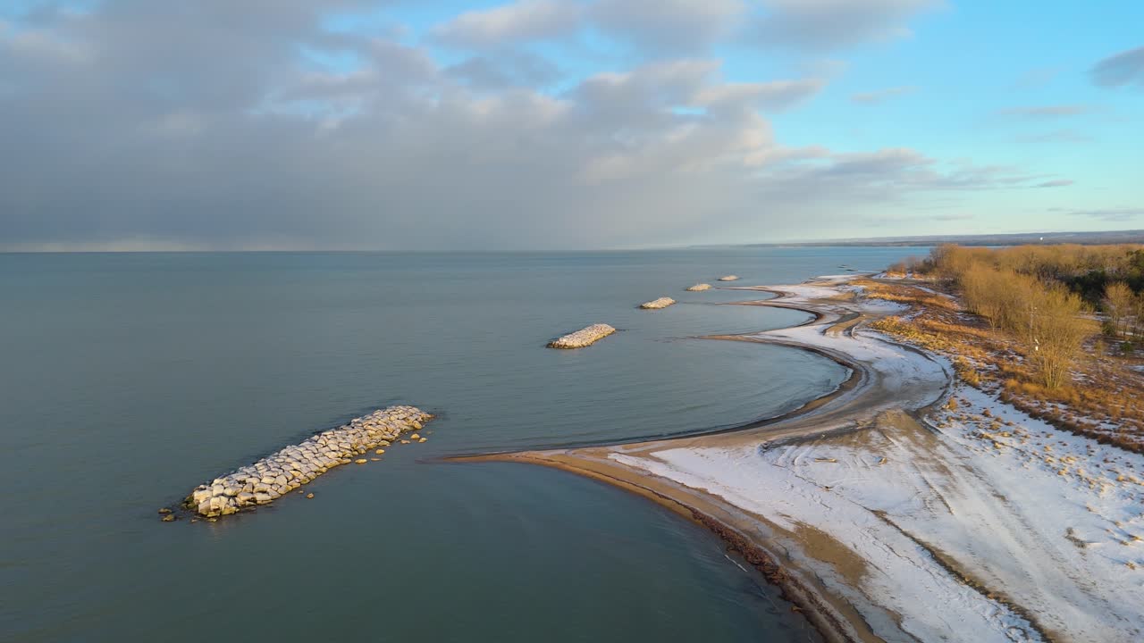 Aerial shot of a Presque Isle State Park beach in the winter at golden hour as a storm is approaching in the distance.