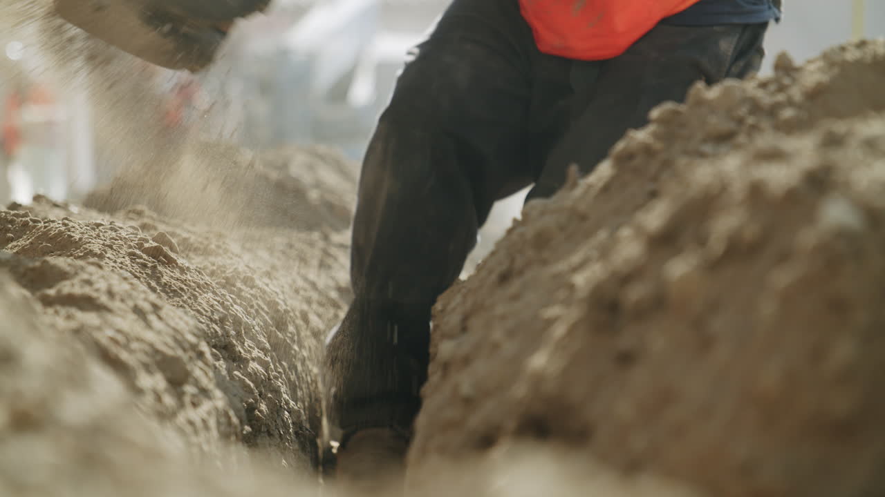 A construction worker digging a trench with a shovel