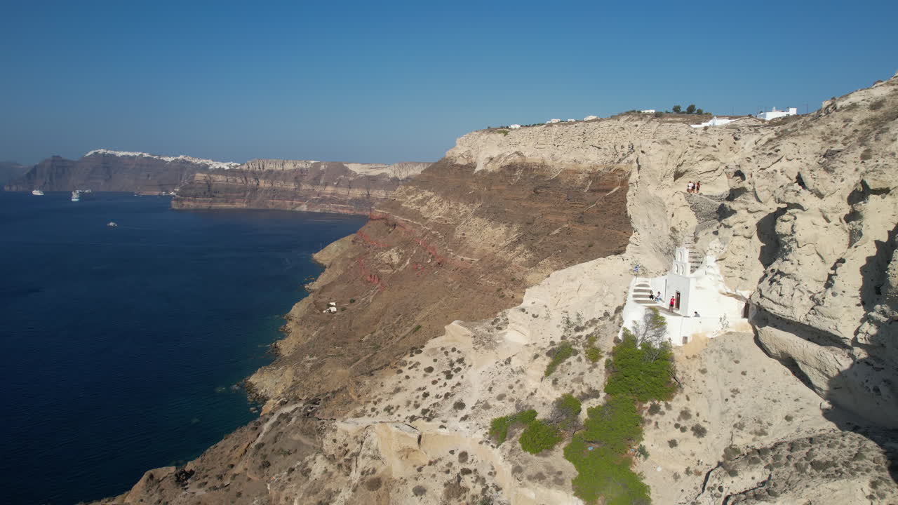 vista aérea de la iglesia ortodoxa griega bajo los acantilados de la isla de santorini, disparo de drones