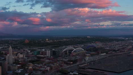 Gran-Toma-Aérea-Alejándose-Del-Distrito-Del-Estadio-De-Seattle-Con-Una-Fresca-Puesta-De-Sol-Rosa-En-El-Fondo