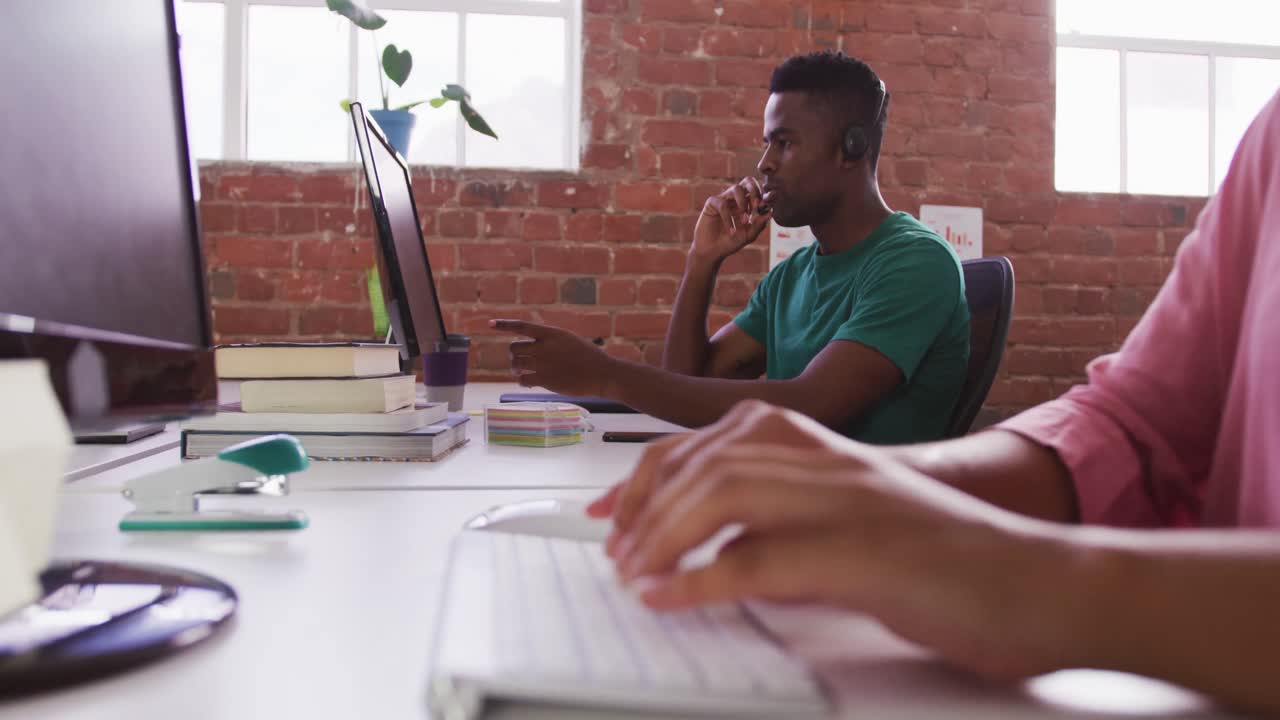 diversi colleghi d'affari seduti a scrivania, maschio in videoconferenza femmina che scrive sulla tastiera