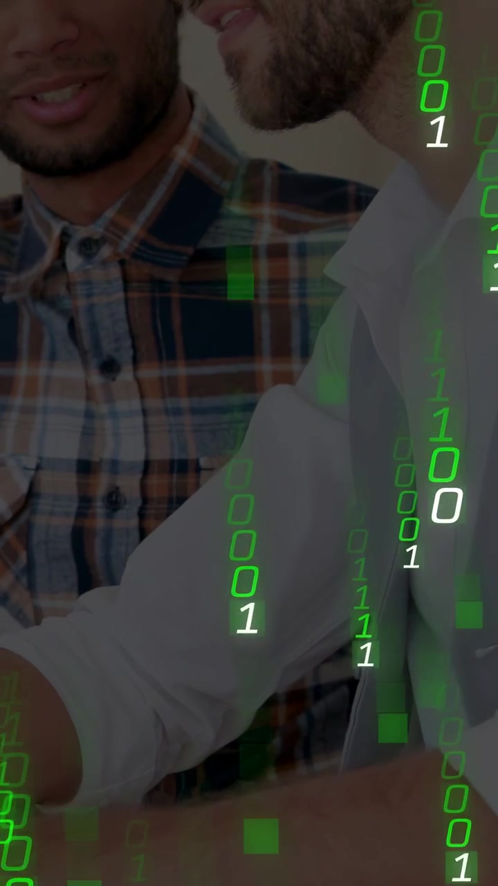 Video vertical: Dos hombres señalando, inclinándose sobre una pantalla con código binario verde sobre sus rostros, para tecnología.