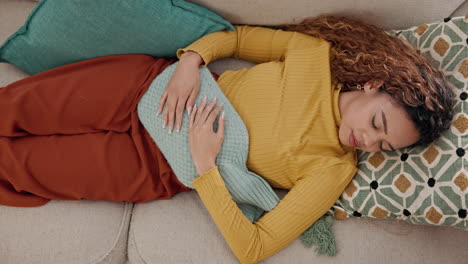 woman laying on couch with a hot water bottle for stomach pain