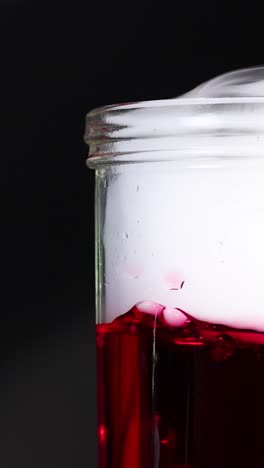 A beaker with red liquid and dry ice creates a smoky, bubbling effect, captured in a dark setting