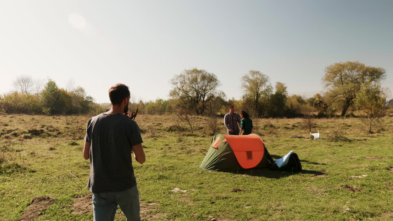 수염 이 있는 남자 가 친구 들 에게 캠프 불 을 위해 불 을 는 데 도움 을 주고 있다