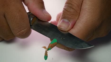 imágenes de manos afilando lentamente un lápiz y algunos lápices de colores con un cuchillo afilado