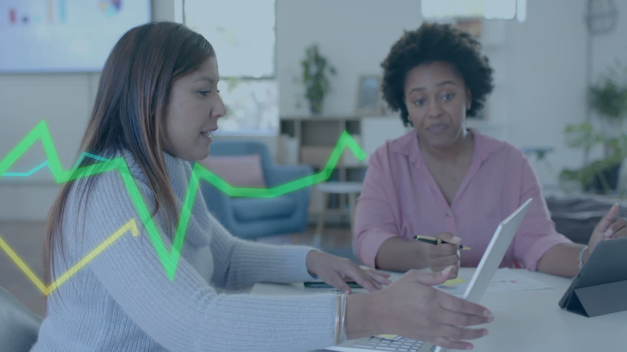Processamento de dados gráficos em interface sobre colegas diversas com laptop e tablet discutindo na mesa