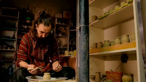 professional potter shaping mug with special tool in pottery workshop