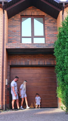 kyiv, ukraine, 25 may 2025: family enjoying time outside home. a family with a child stands near their house, sharing a moment together during a sunny day in a residential area