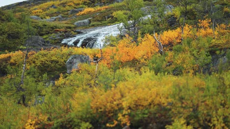 a waterfall on the shallow mountain river surrounded by an autumn tundra landscape