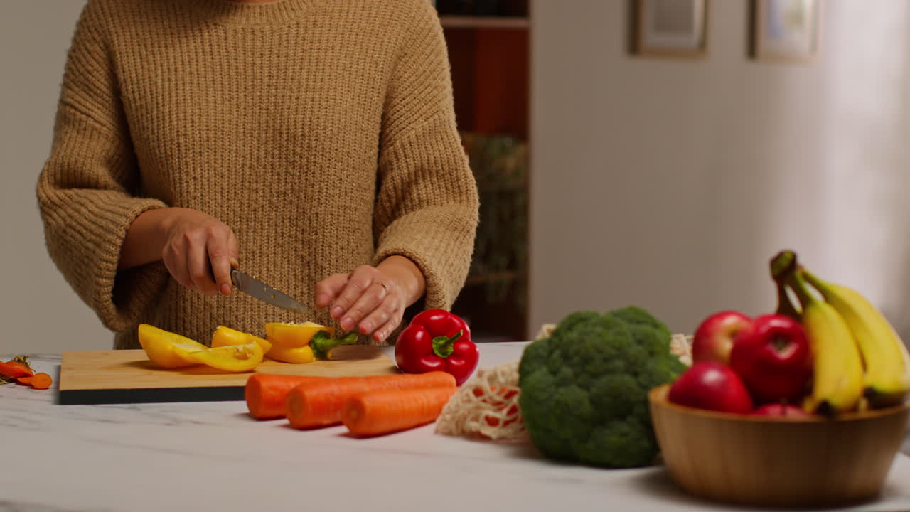 primer plano de una mujer en casa en la cocina preparando verduras frescas saludables para una comida vegetariana o vegana cortando pimienta amarilla a bordo 1