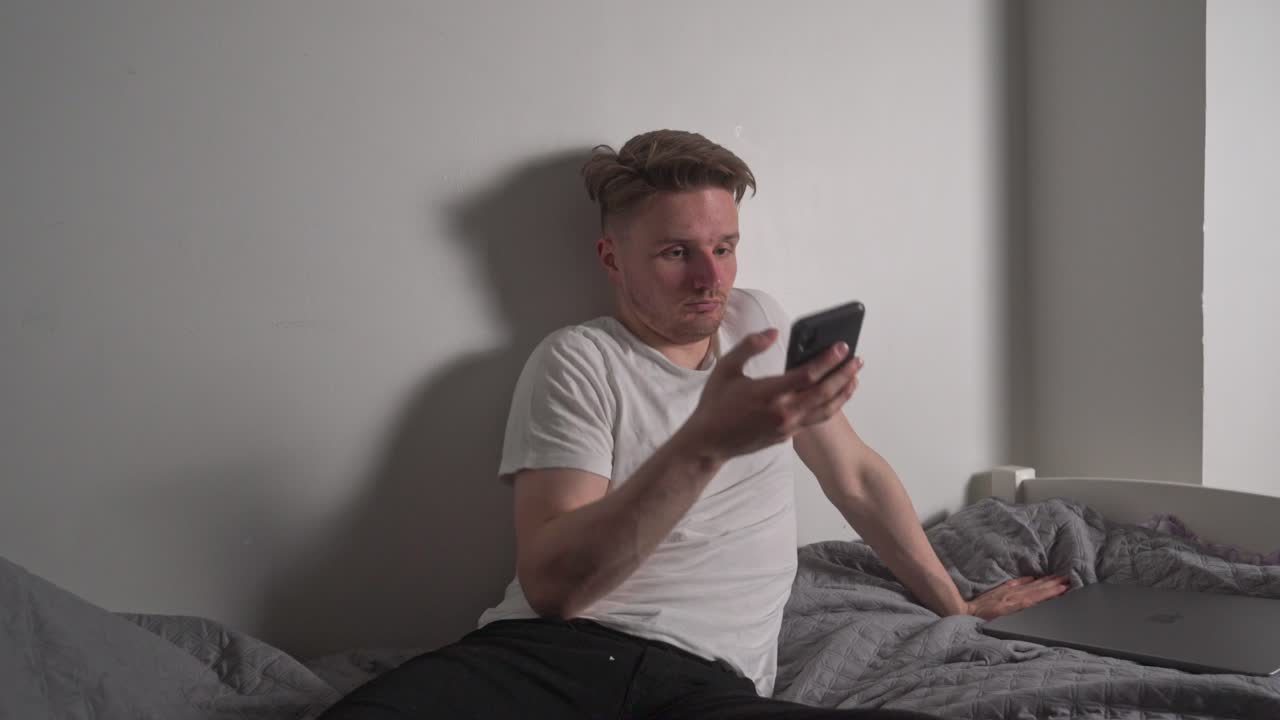 молодой человек плюхается на кровать, чтобы написать другу сообщение о следующих выходных и последнем проекте на работе, который потребует много внимания