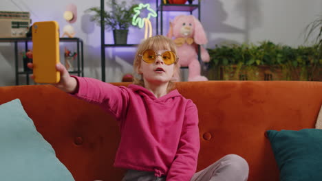 child kid girl taking selfie on smartphone communicating video call home online with subscribers