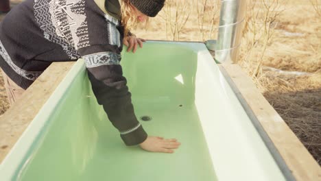 남자는 막기를 입하고 뜨거운 욕조를 물로 채우기 시작합니다.