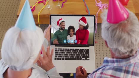 Pareja-Mayor-Caucásica-Con-Sombreros-De-Fiesta-En-Video-Chat-Portátil-Durante-La-Navidad-En-Casa