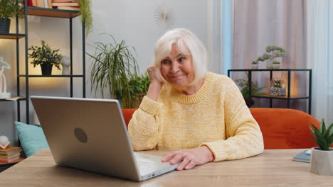 Senior-grandmother-woman-at-home-looking-at-camera-making-video-conference-call-with-friends-family