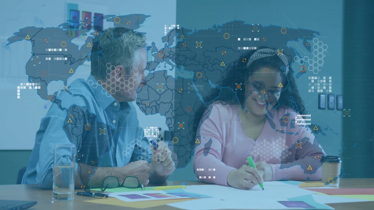 Man pointing at swatches, woman taking notes, digital map overlaying icons during business meeting