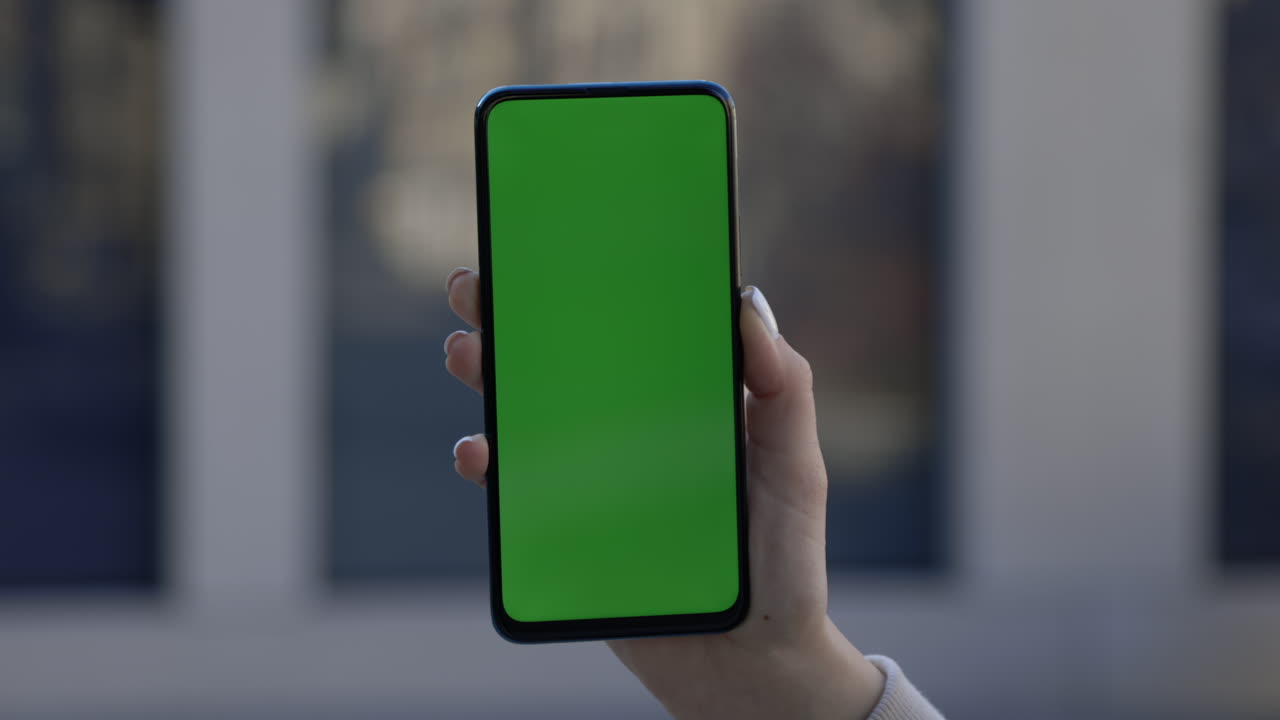 Woman Holding Smartphone with Green Screen Display