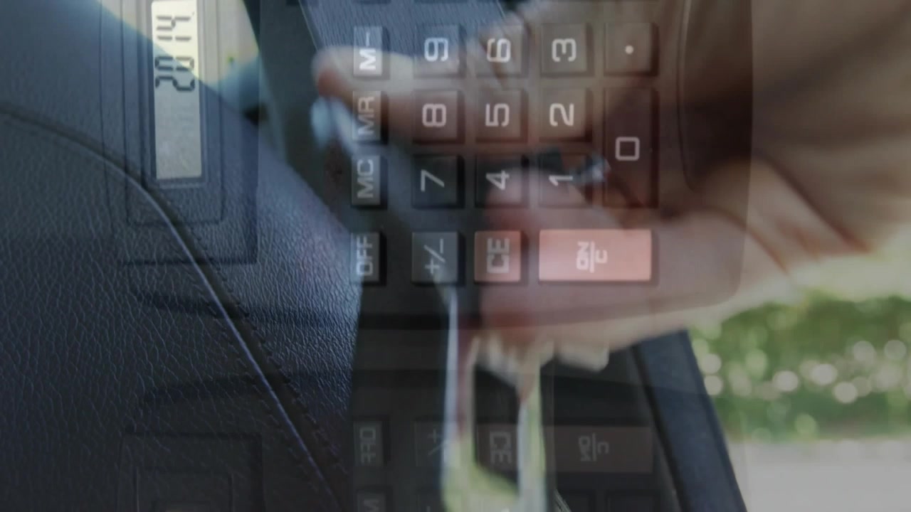 Animazione di una calcolatrice che cade sopra la mano inquadrata di un uomo caucasico che allaccia la cintura di sicurezza in auto.
