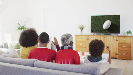 Familia-Birracial-Viendo-Televisión-Con-Pelota-De-Rugby-En-El-Estadio-En-La-Pantalla