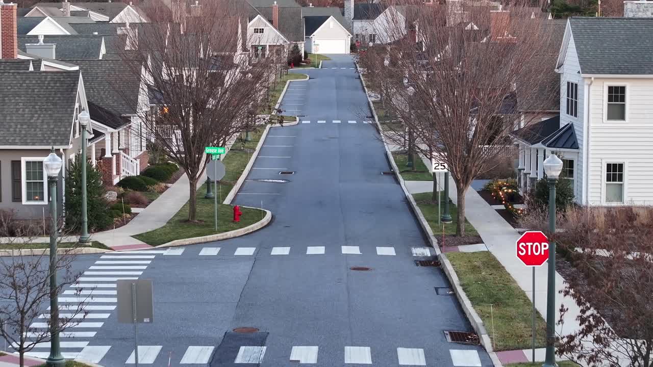 Empty road in new development housing area of USA. Winter Christmas scene with leafless trees on sidewalk. Afrika forward dolly shot,. Modern houses and homes in suburb of PA, United States.