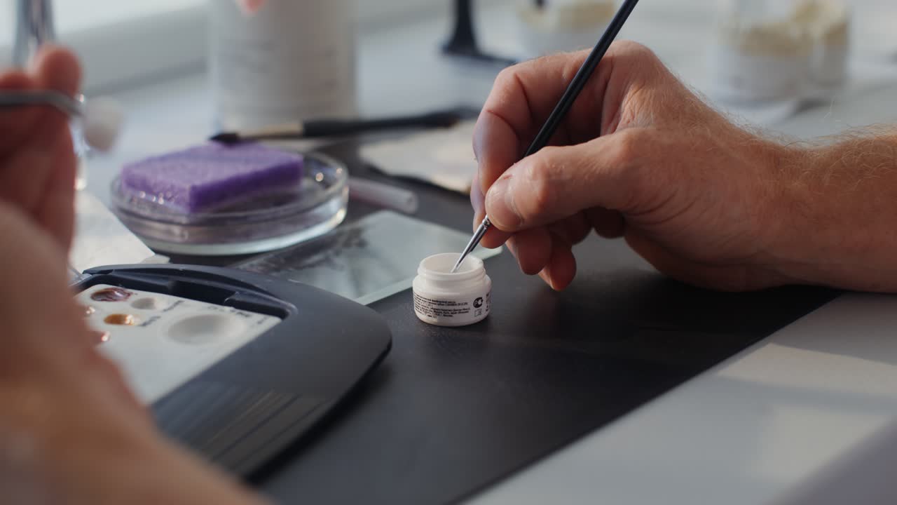 técnico dental que aplica resina para la restauración dental